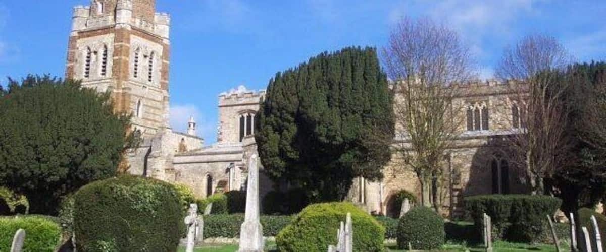 A historic church with a tall bell tower and well-maintained gardens.