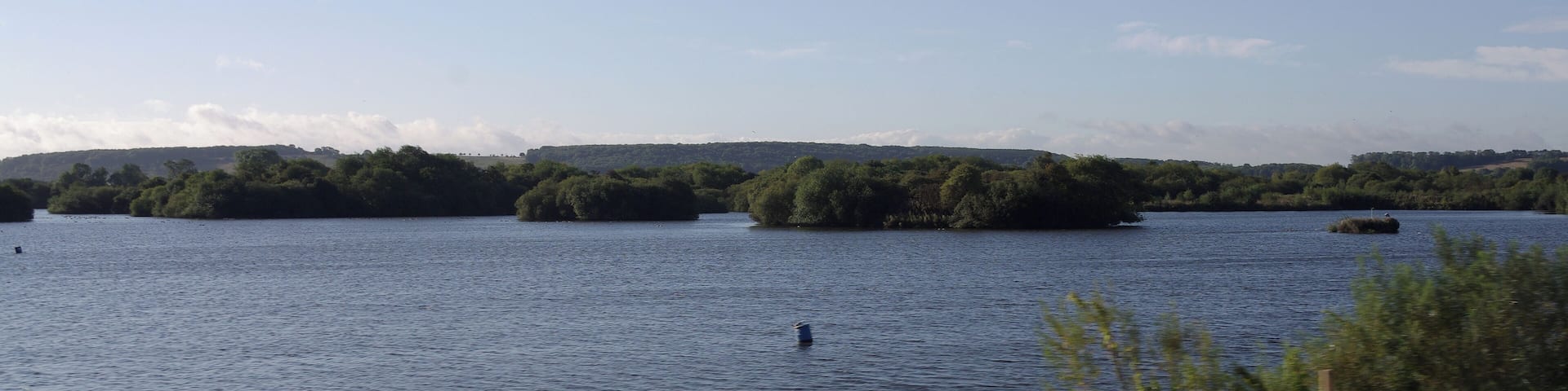 Early morning sunlight on the waters of the Attenborough Nature Reserve, seen from a passing train.