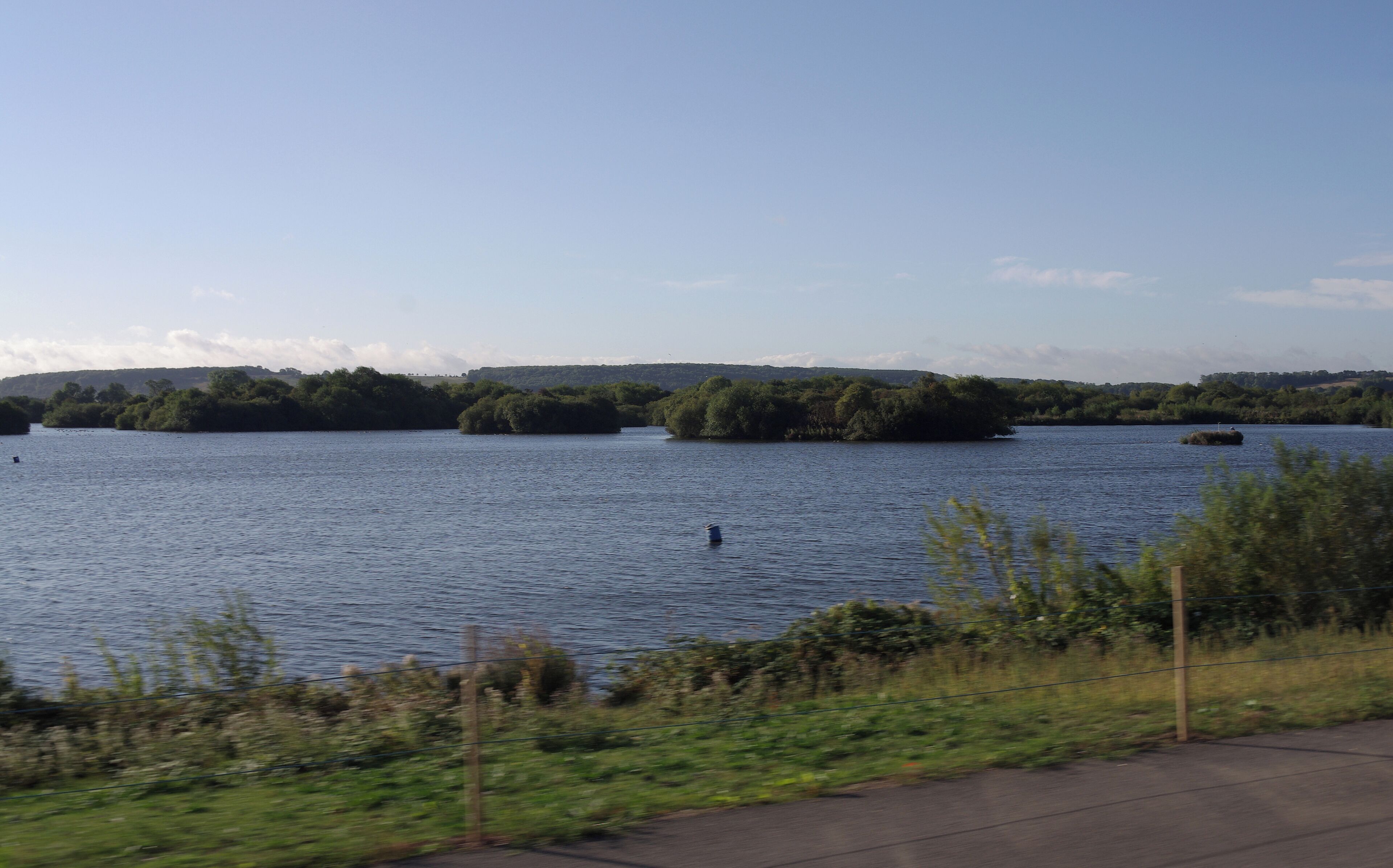 A calm lake with several small islands surrounded by dense greenery.