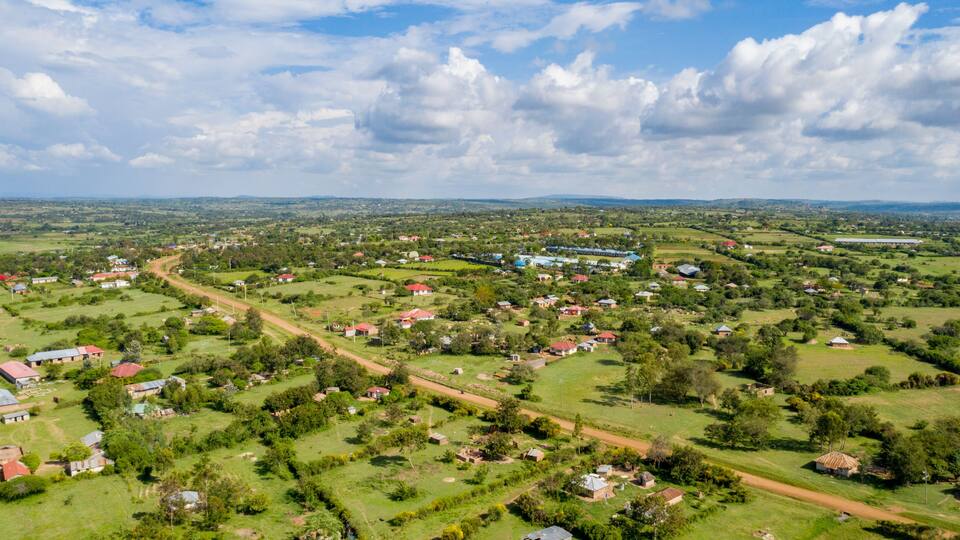 A rural landscape with scattered houses, green fields, and a winding road.