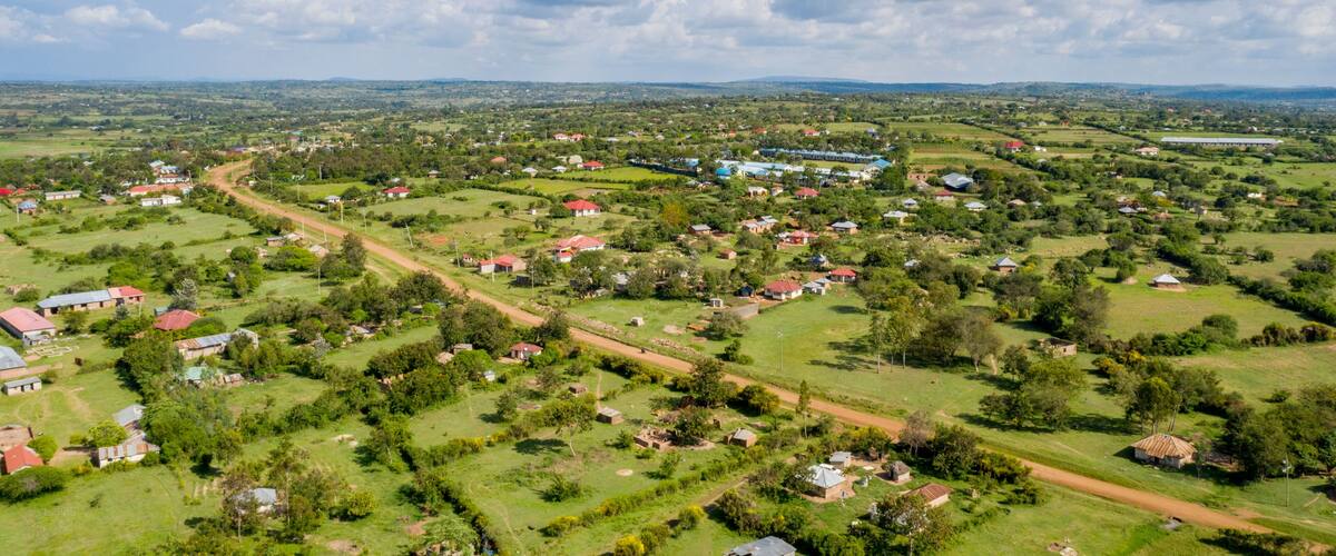 A rural landscape with scattered houses, green fields, and a winding road.