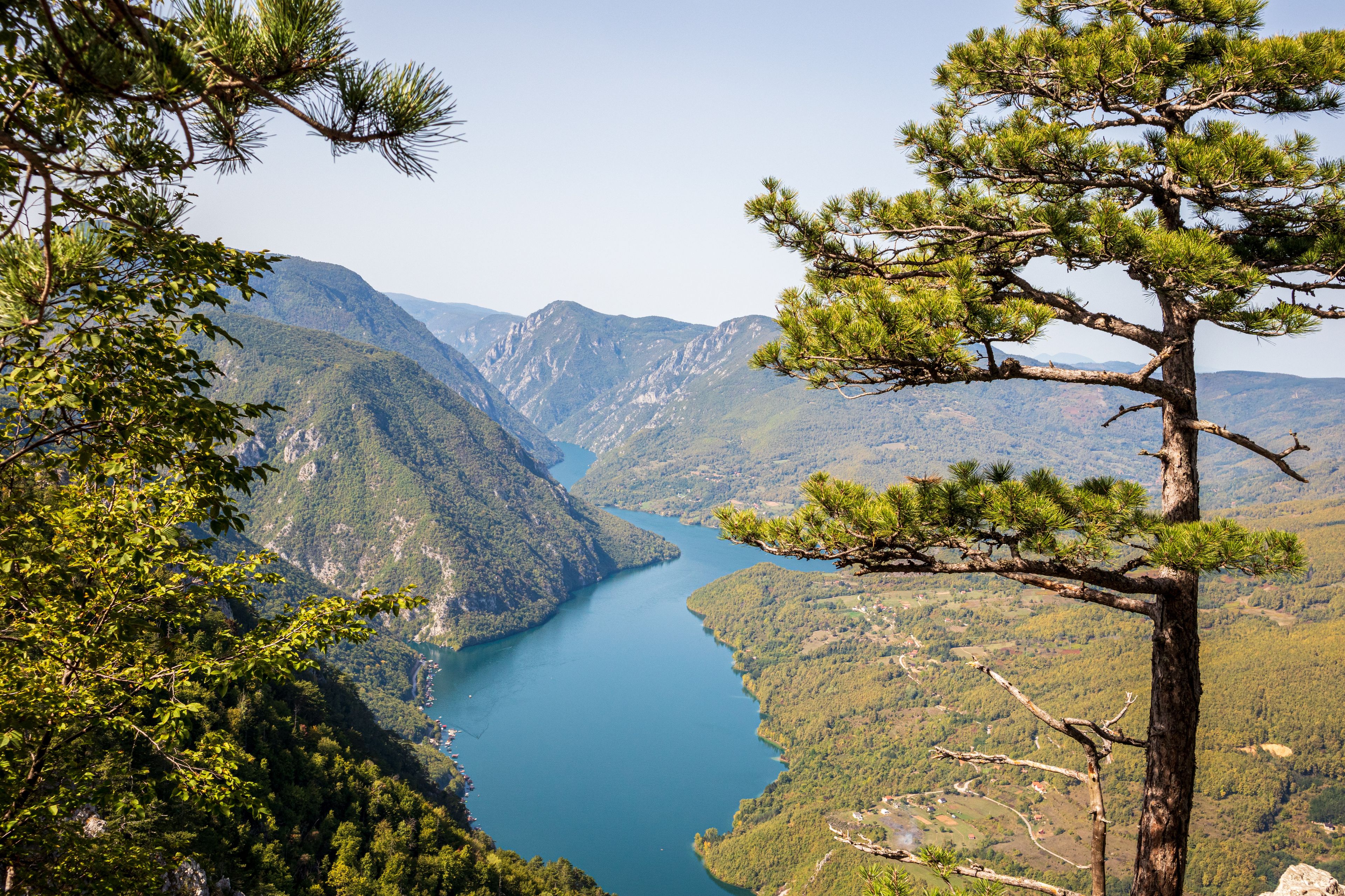A mountainous landscape with a clear blue lake surrounded by dense forests and pine trees.