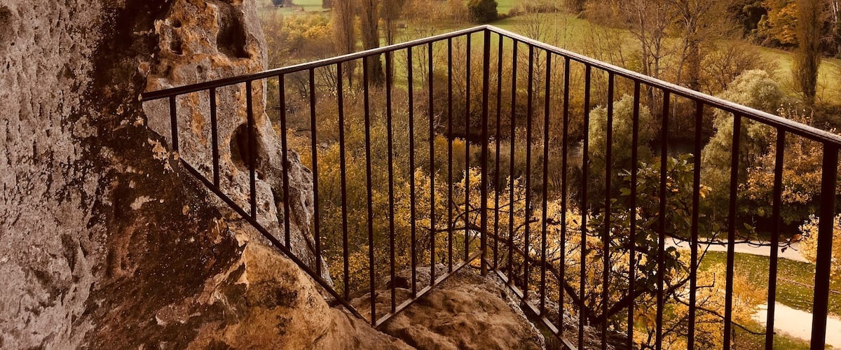 A stone archway overlooking a valley with autumn foliage and distant hills.