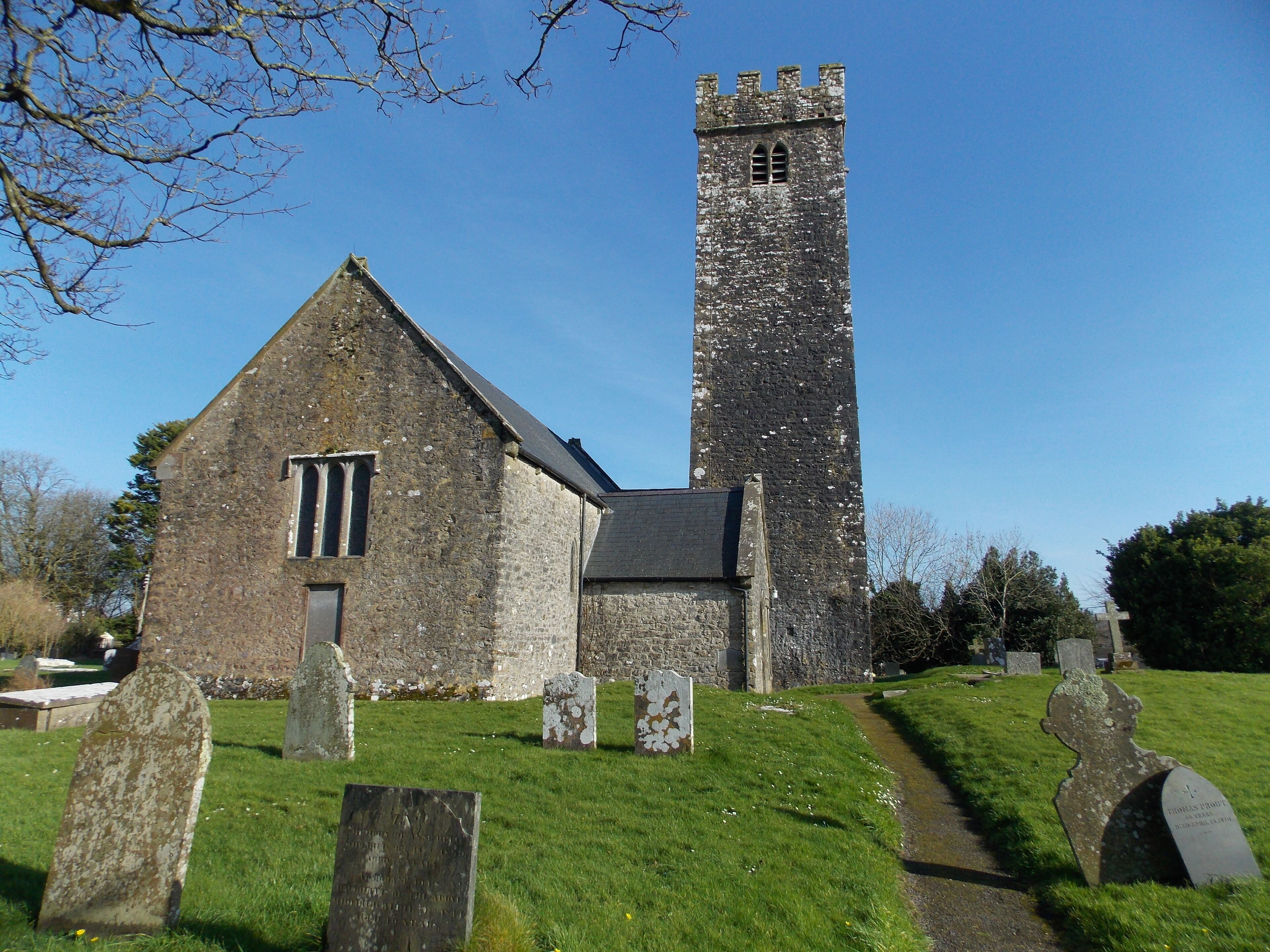 A church with a tall tower and gravestones in the foreground.