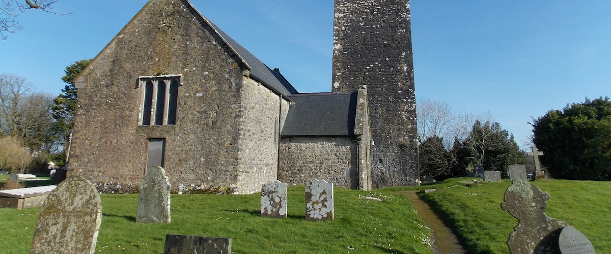 A church with a tall tower and gravestones in the foreground.