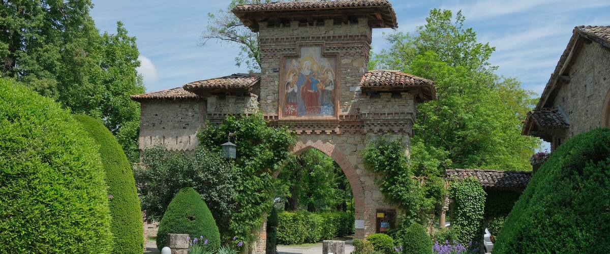 A historic stone building with a tiled roof and a fresco mural.