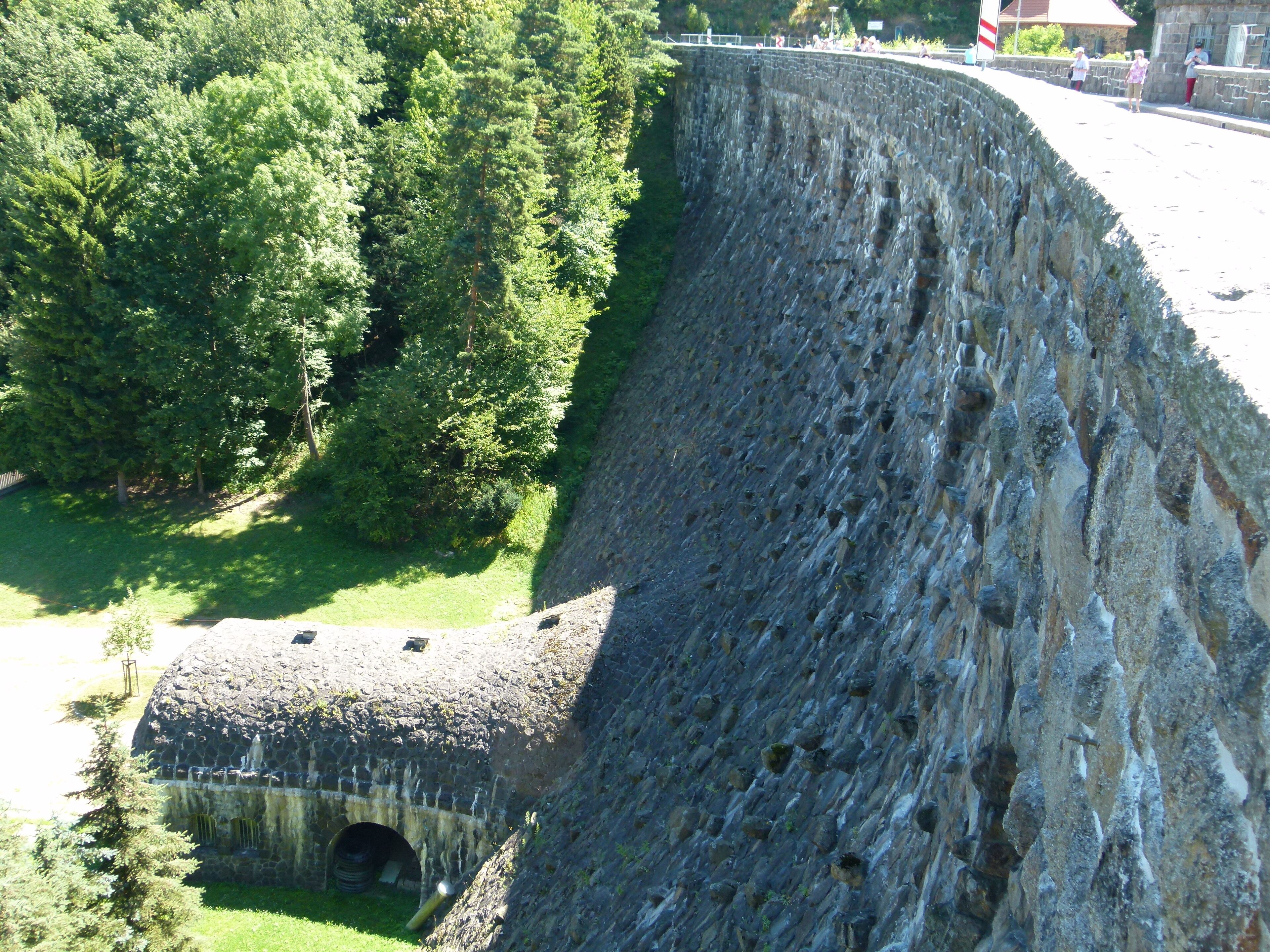 A large dam with a tunnel entrance, surrounded by dense greenery.