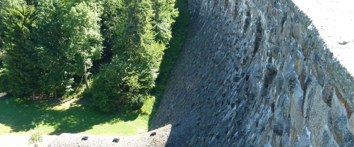 A large dam with a tunnel entrance, surrounded by dense greenery.