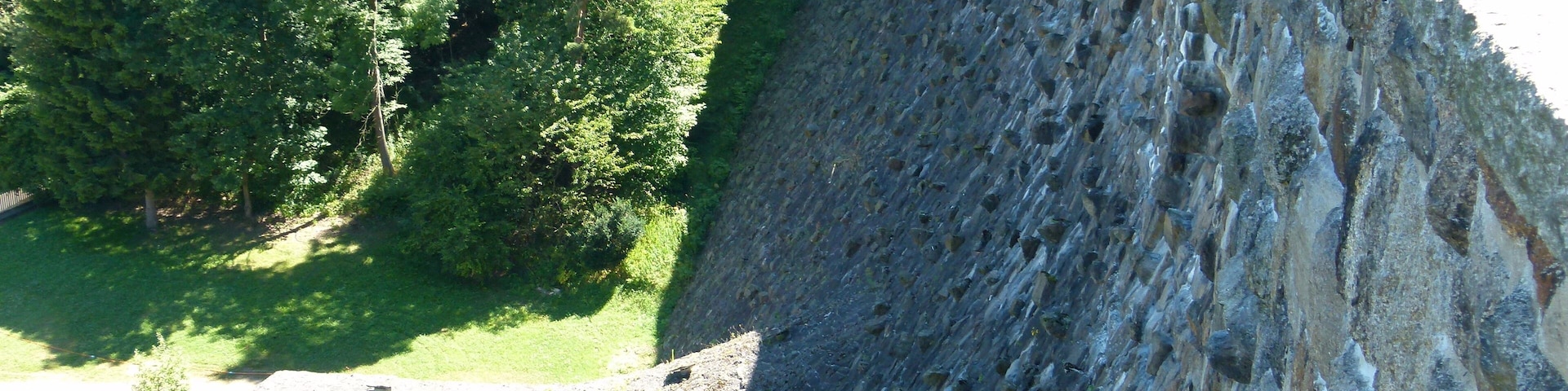 A large dam with a tunnel entrance, surrounded by dense greenery.