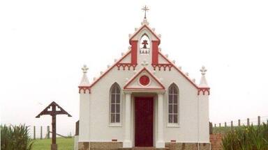 A small white church with a red door and a cross on top.
