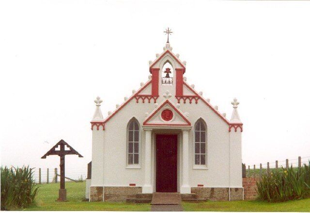 A small white church with a red door and a cross on top.