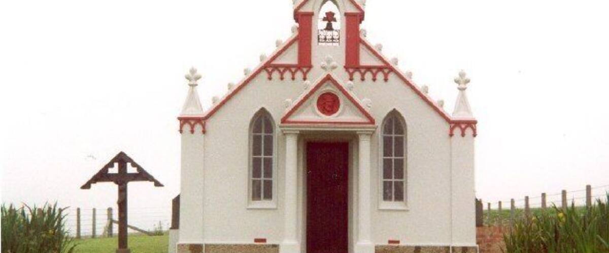 A small white church with a red door and a cross on top.