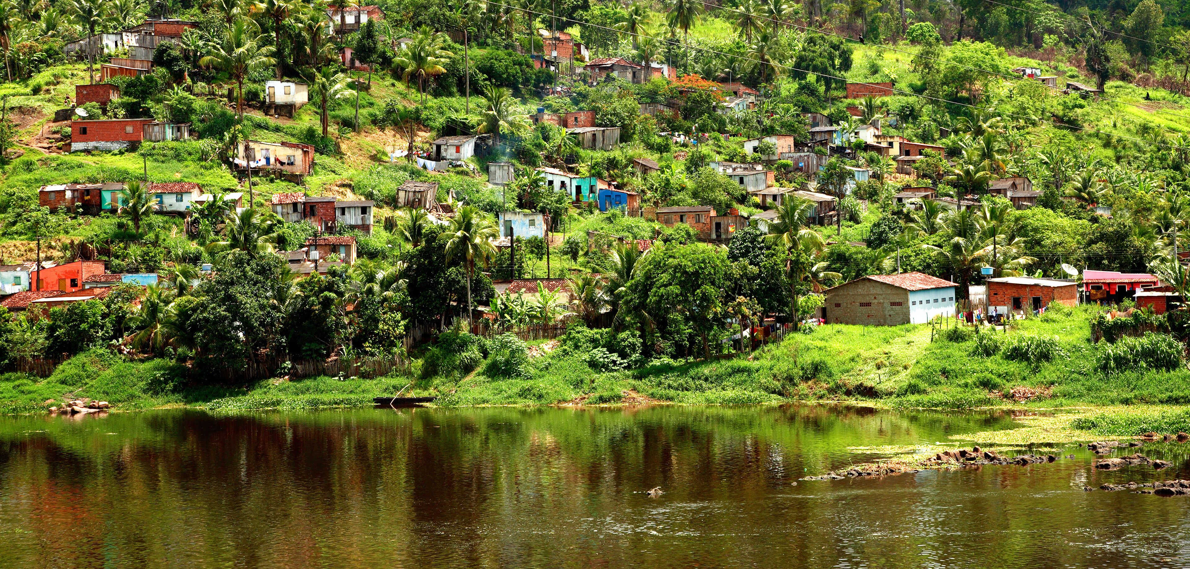 A hillside village with houses, a river, and lush greenery.