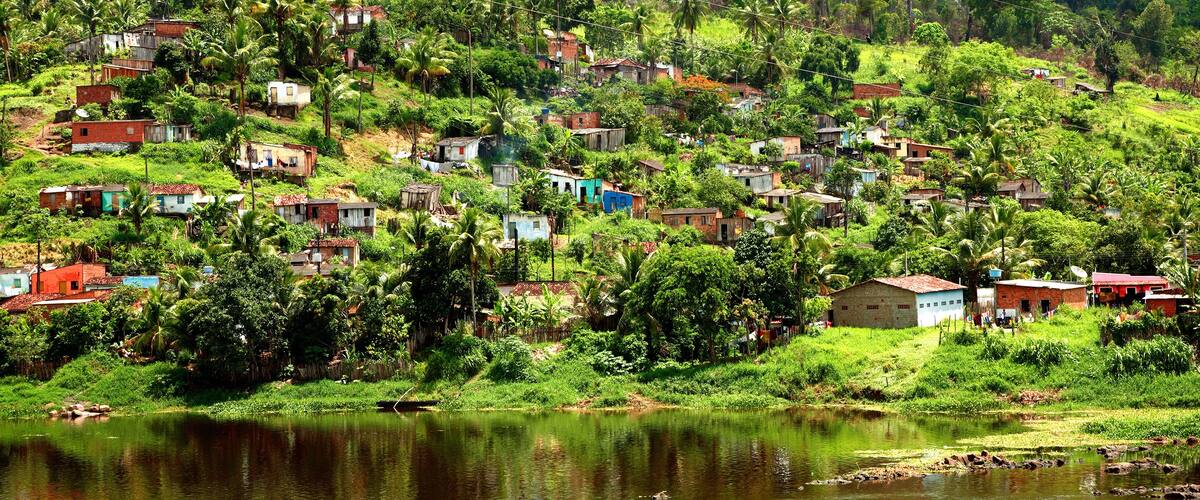 A hillside village with houses, a river, and lush greenery.
