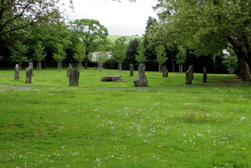 A grassy field with standing stones and trees.