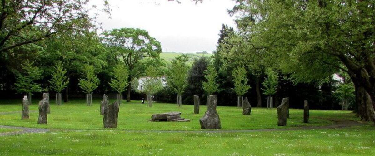 A grassy field with standing stones and trees.