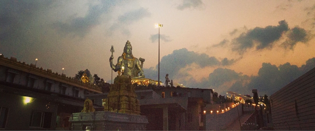 A statue of a deity on a temple platform with a bridge in the background.