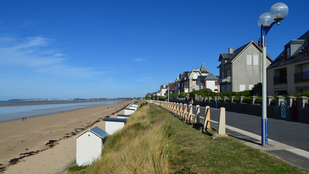 Une plage bordée de maisons, un ciel bleu et dégagé, et un lampadaire.