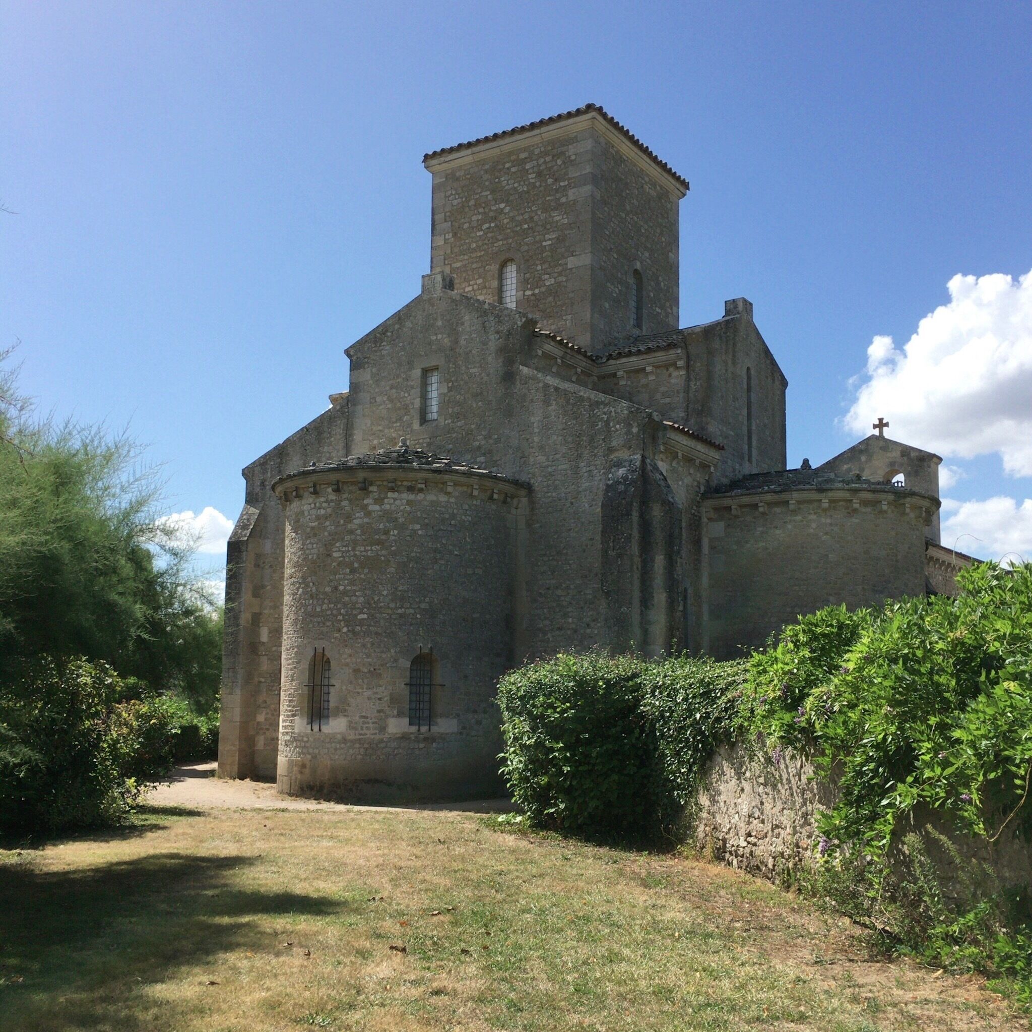 A historic stone church with a bell tower and a circular window.