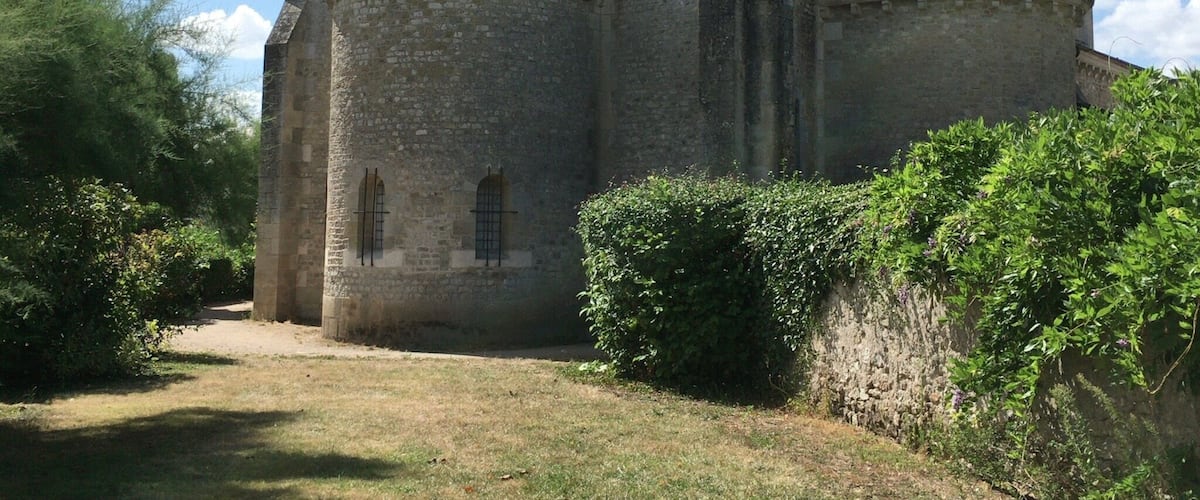 A historic stone church with a bell tower and a circular window.