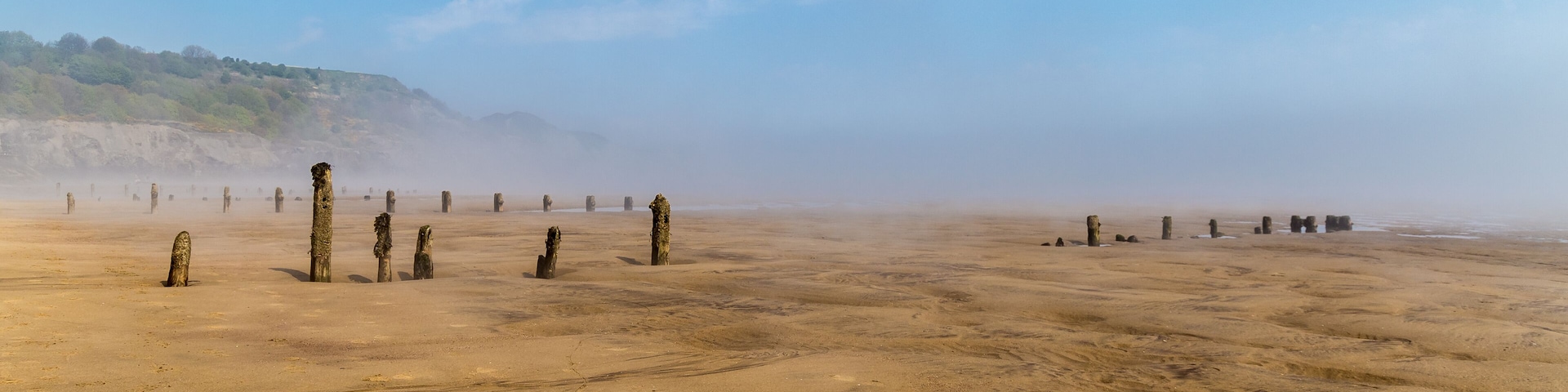 Paisaje desértico con antiguos pilares de piedra dispersos en la arena.