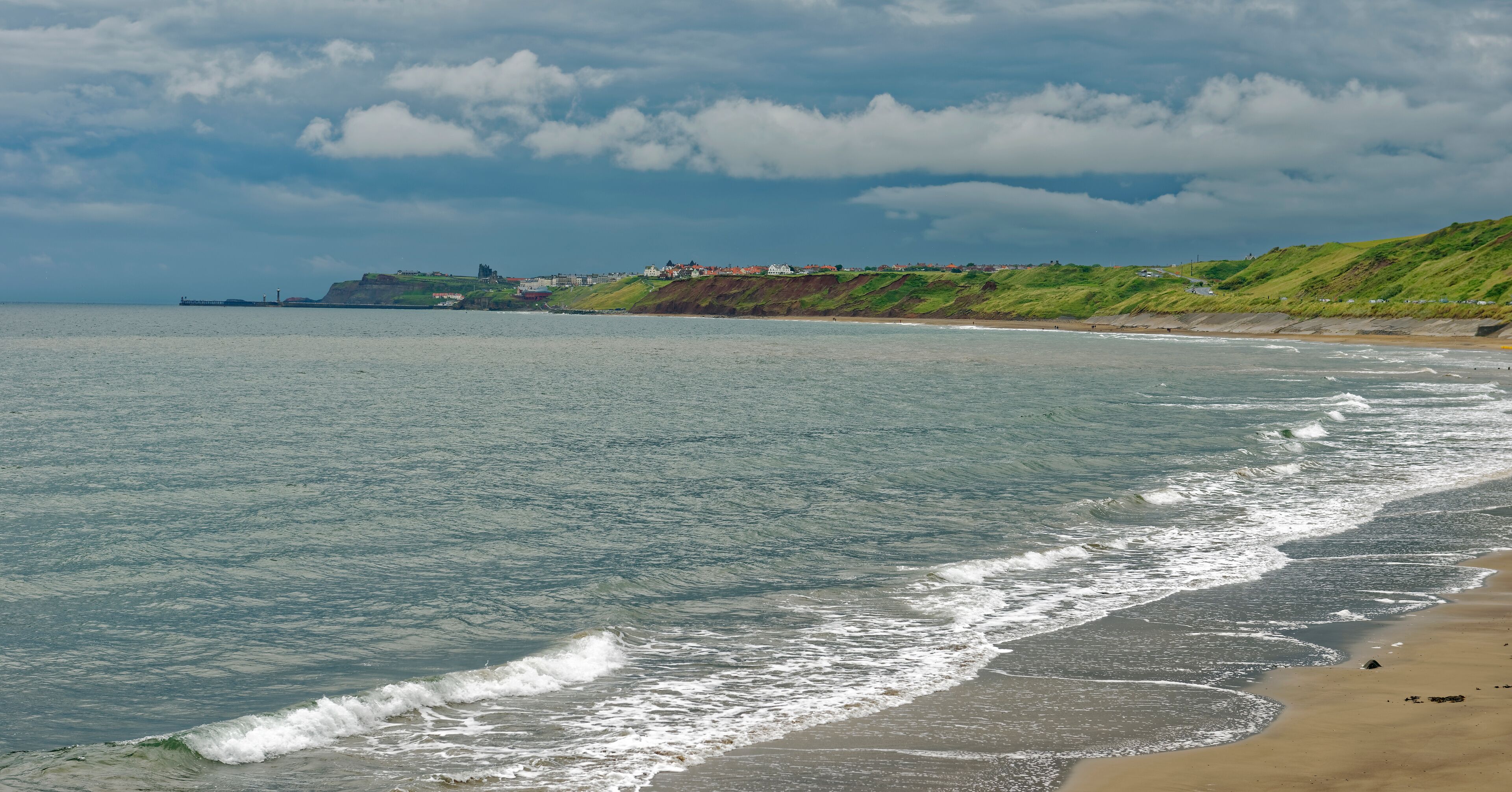 Beach view under a threatening sky of the coastline from Sandsend to Whitby in North Yorkshire, England