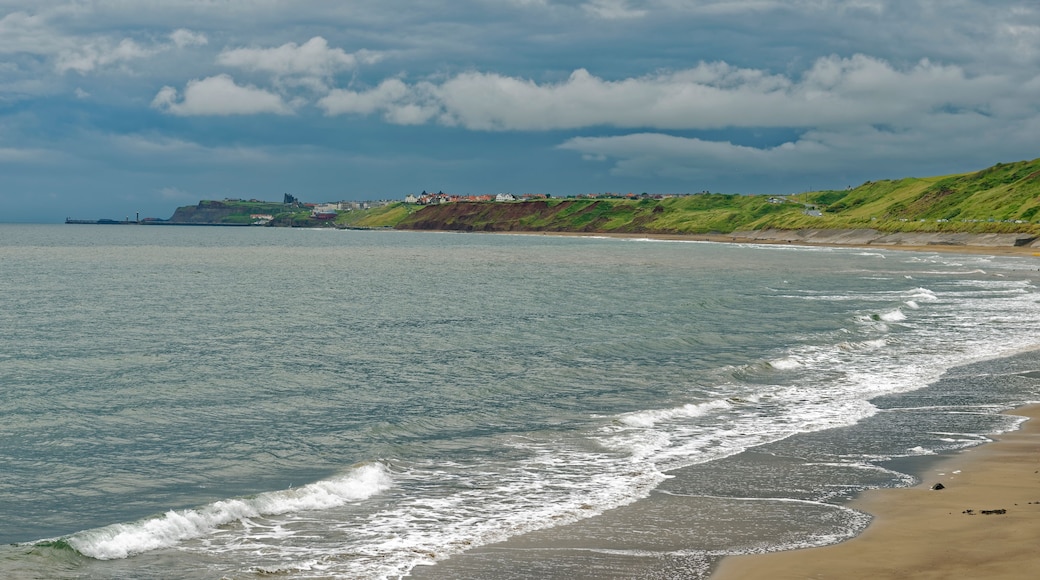Beach view under a threatening sky of the coastline from Sandsend to Whitby in North Yorkshire, England