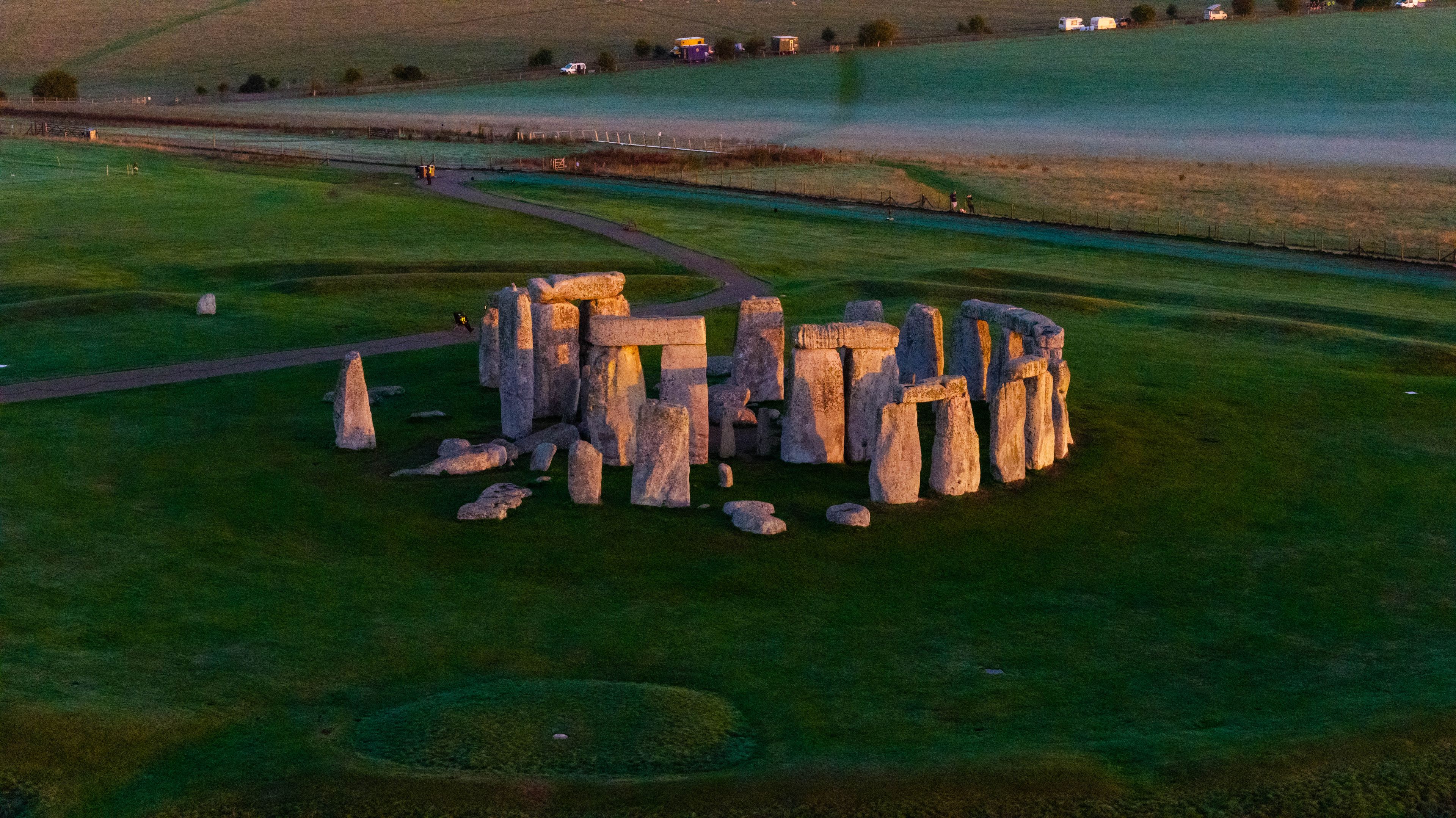 Stonehenge, a prehistoric monument with standing stones arranged in a circular layout, surrounded by green fields and a river.