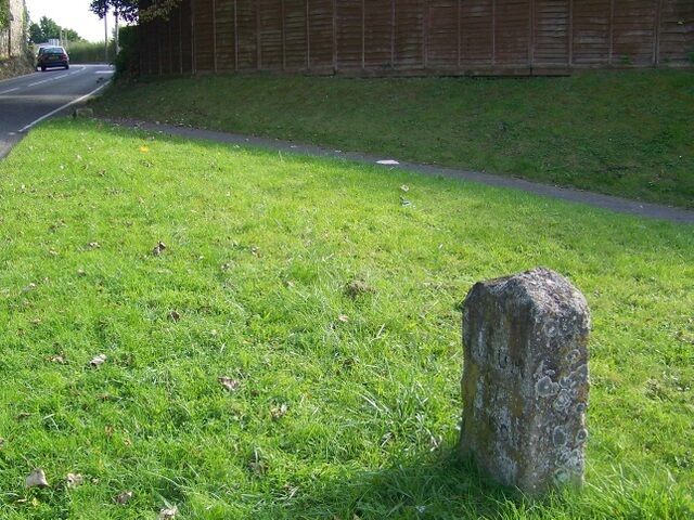 A grassy area with a stone monument and a road with a car in the distance.