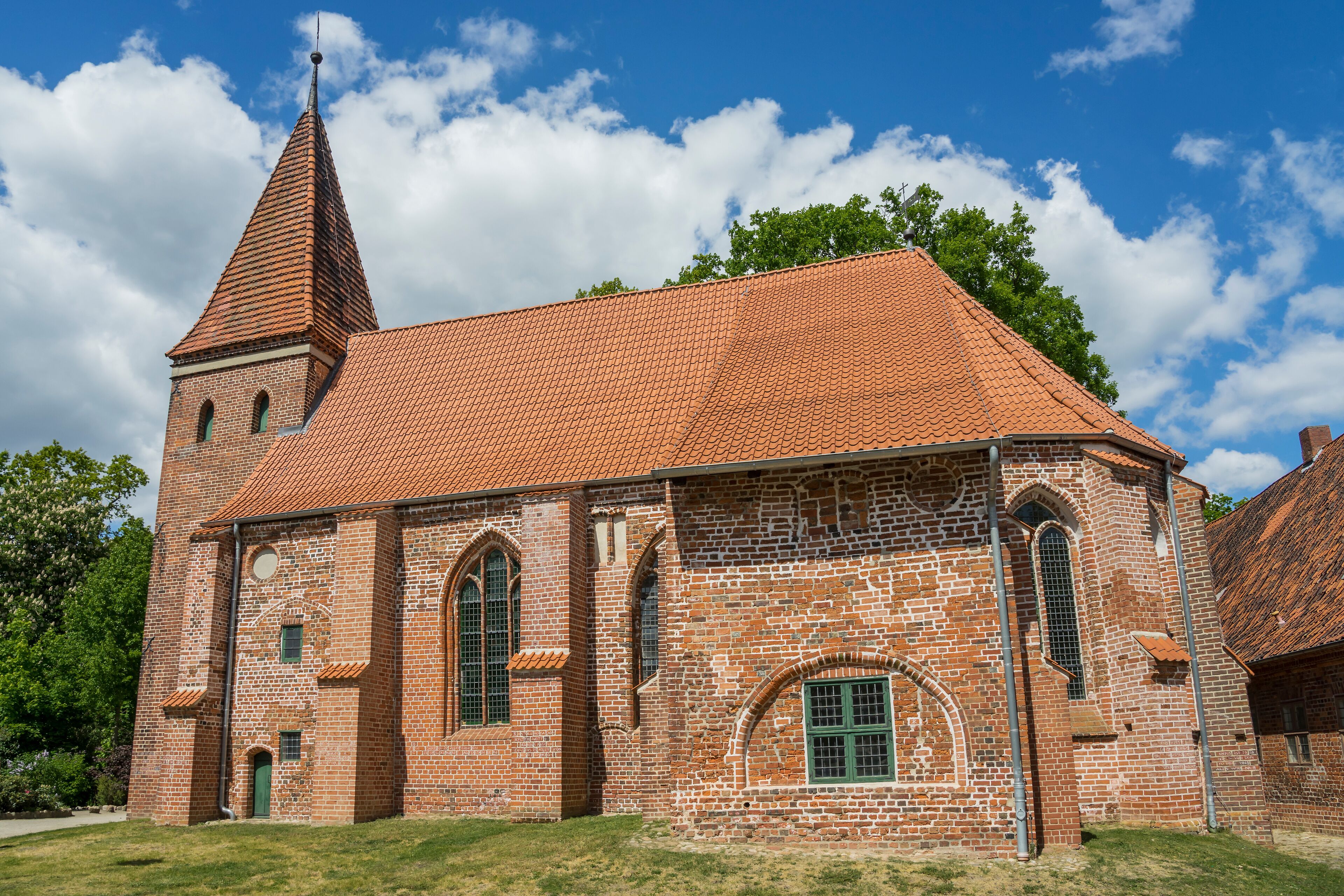 A brick church with a red-tiled roof and a tall tower.