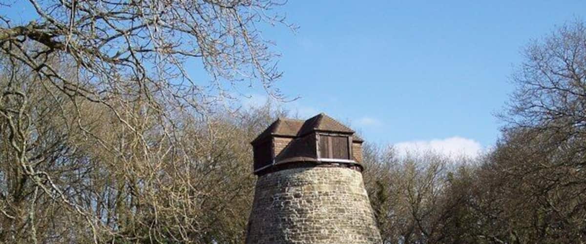 A stone tower with a wooden roof surrounded by trees.