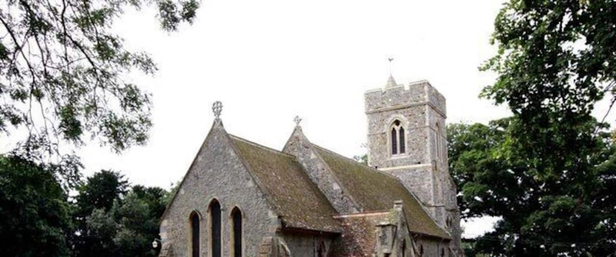 A historic church with a prominent tower and a graveyard with headstones.