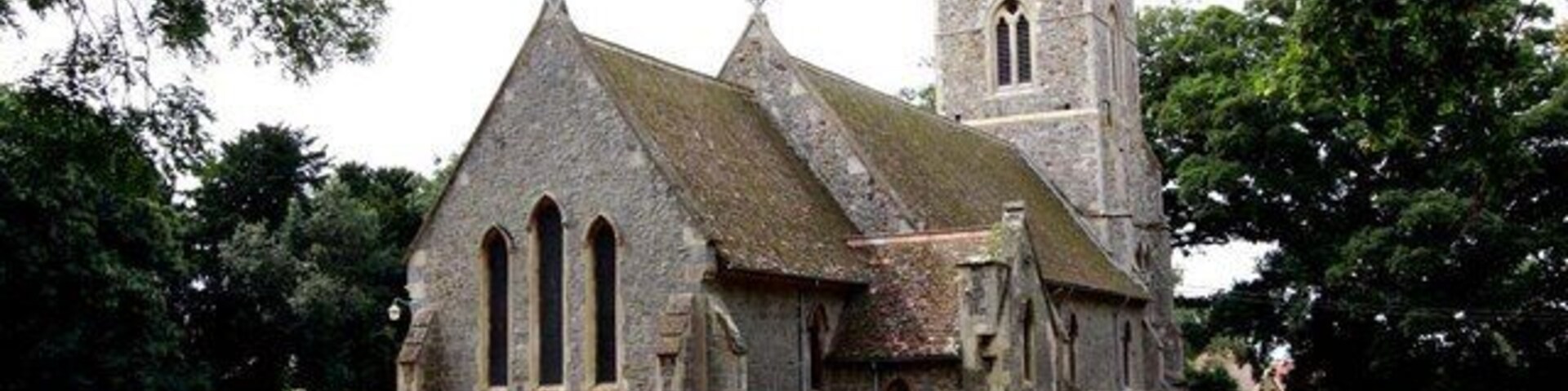 A historic church with a prominent tower and a graveyard with headstones.