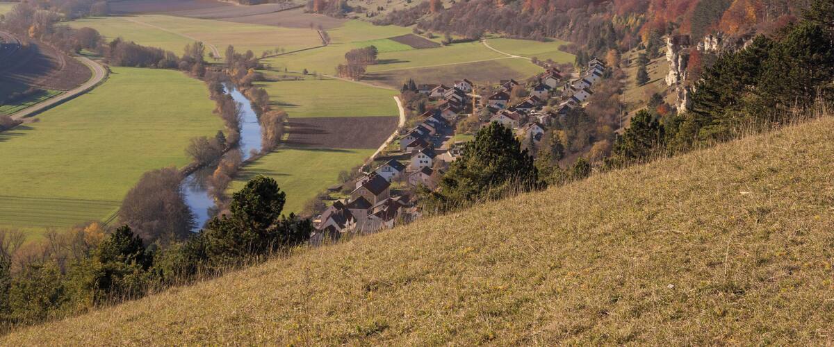 A valley with a river, fields, and a village on a hillside.
