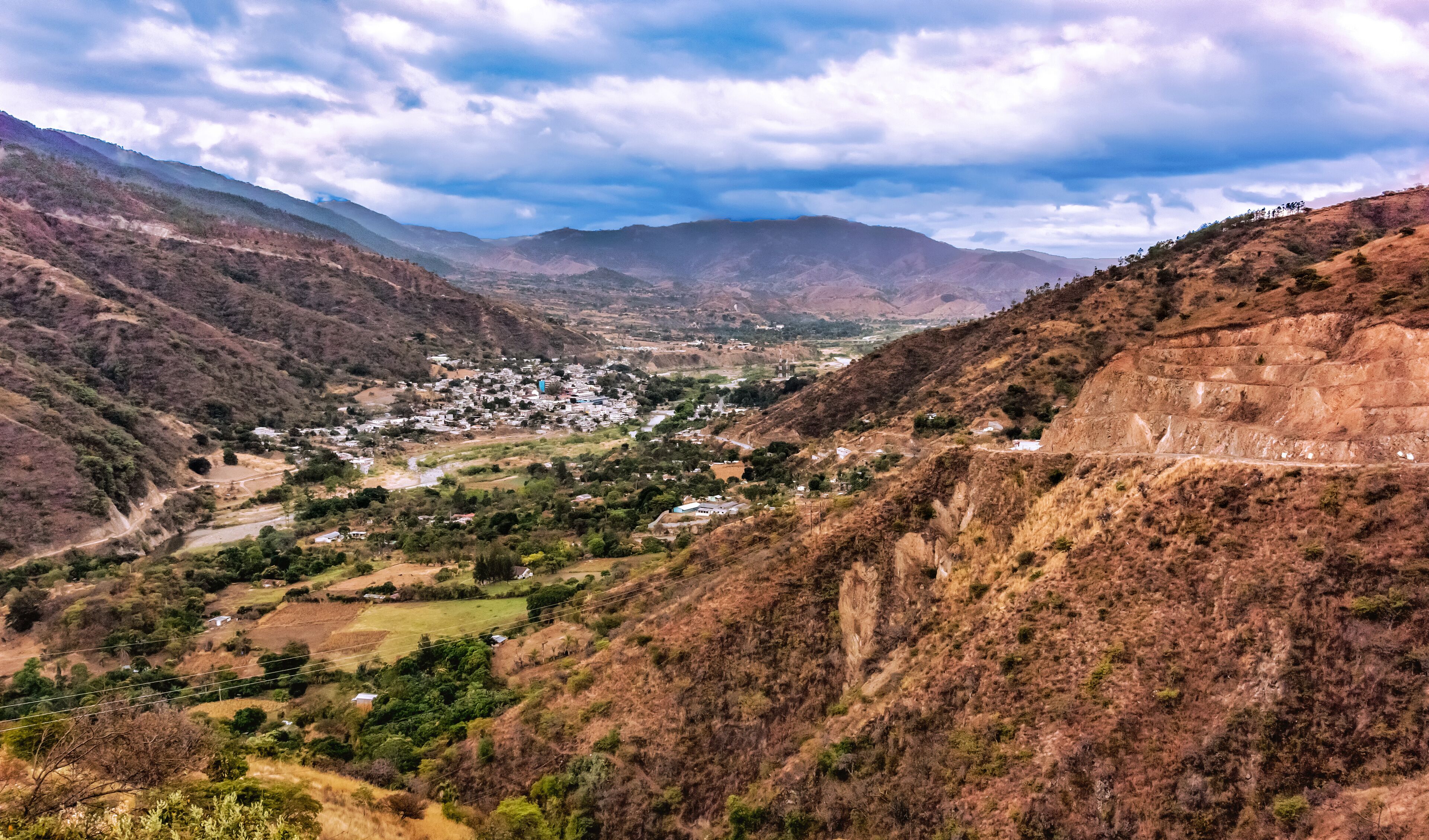 A valley with a small town surrounded by mountains and a river.