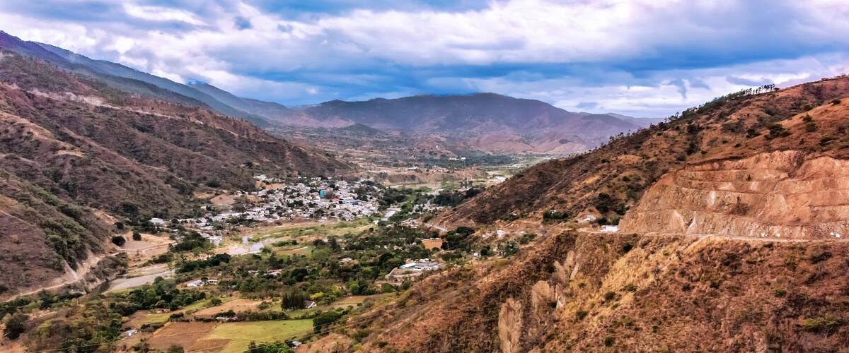 A valley with a small town surrounded by mountains and a river.