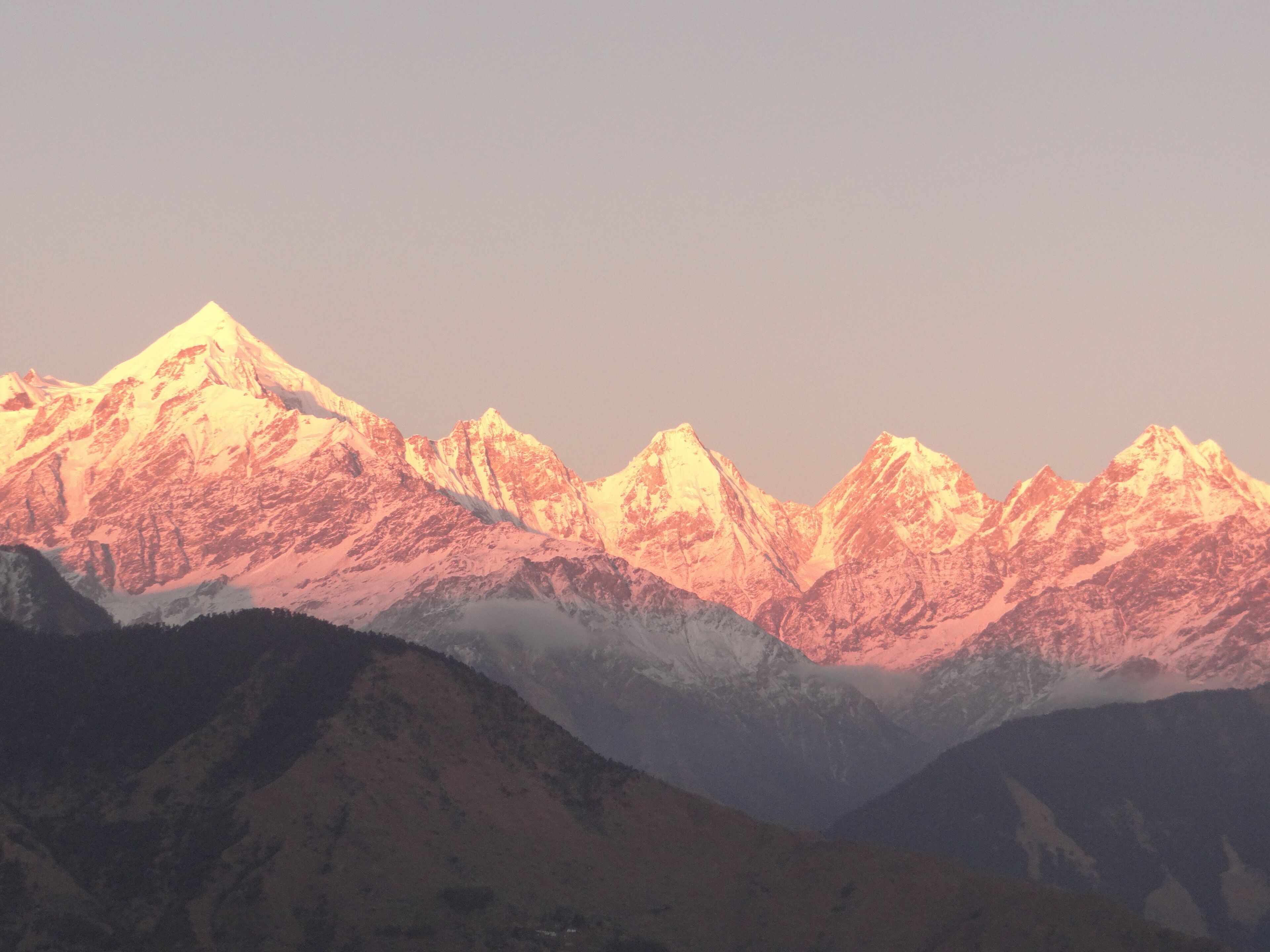 A range of snow-capped mountains with a valley in the foreground.