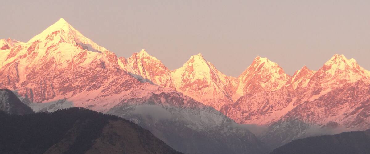 A range of snow-capped mountains with a valley in the foreground.