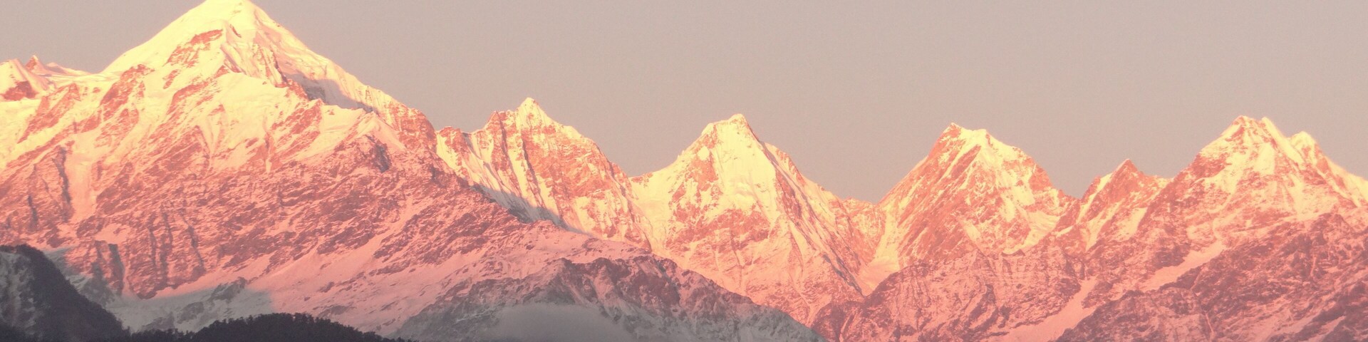 A range of snow-capped mountains with a valley in the foreground.