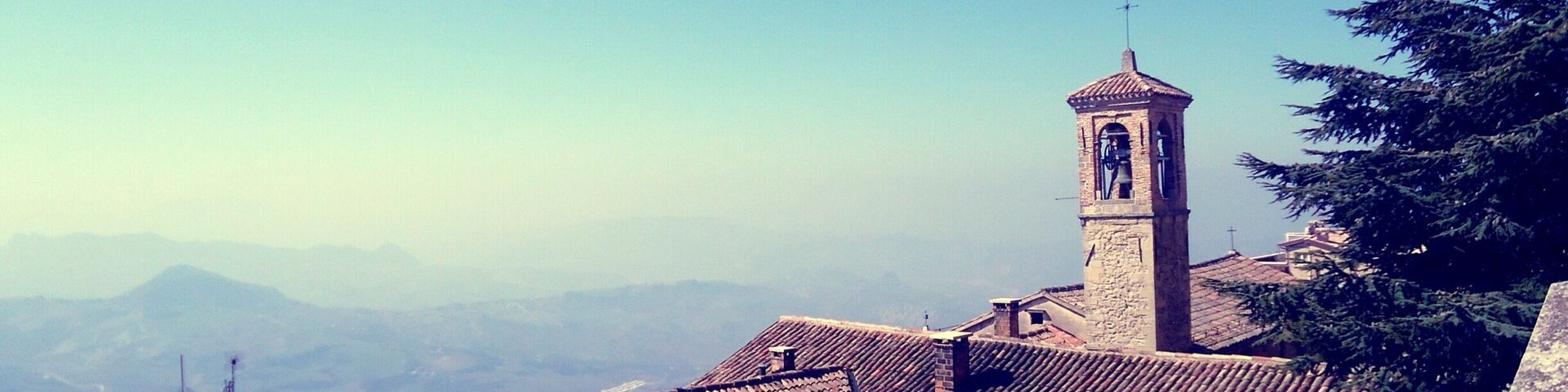 A church with a bell tower and tiled roofs in a mountainous area.