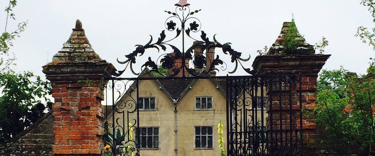 A historic building with a wrought iron gate, brick pillars, and a unicorn statue.