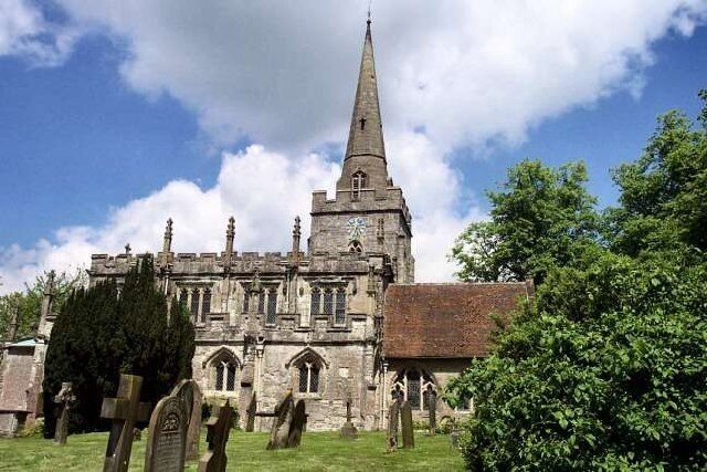A historic church with a tall spire, surrounded by a cemetery.