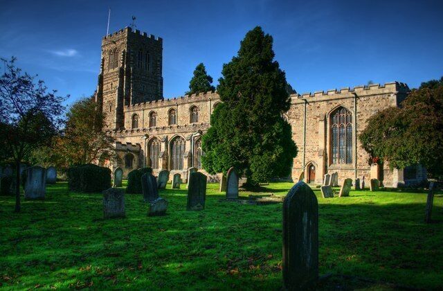 A historic church with a tall tower, surrounded by a cemetery with headstones.