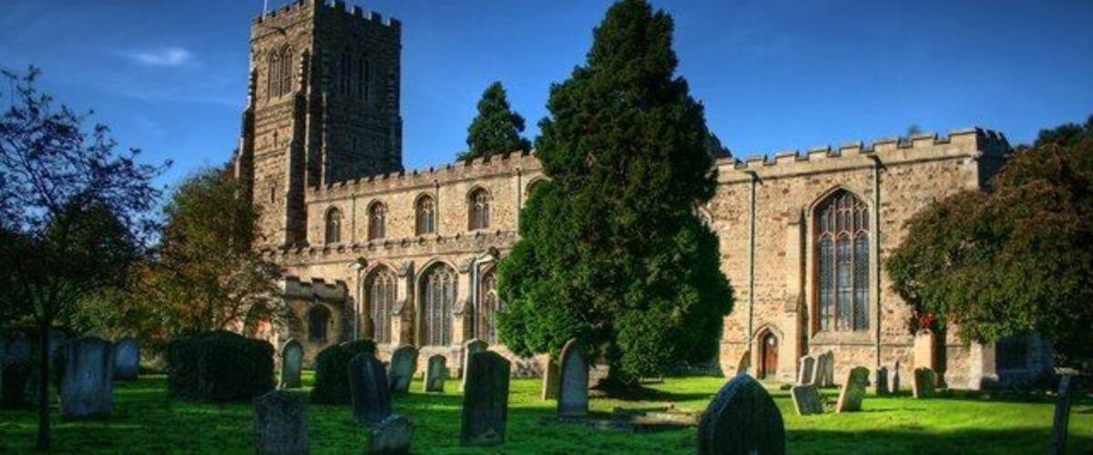 A historic church with a tall tower, surrounded by a cemetery with headstones.
