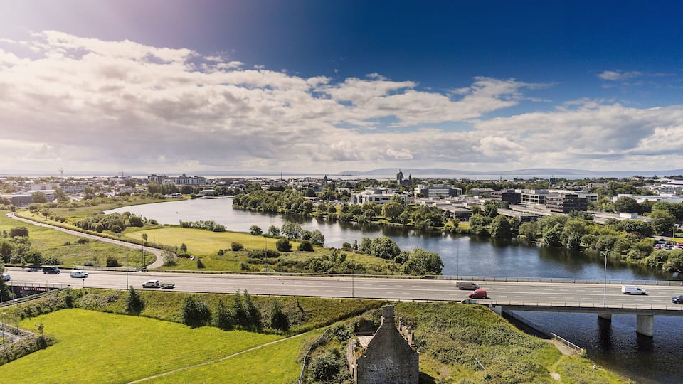 Aerial view, Galway city, Terryland castle, river Corrib, cathedral, cloudy sky, sun flare, sunny day. Ireland.