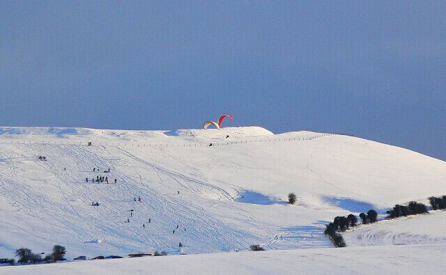 Gliders and sliders, Liddington Castle As ever when the wind is in the north, paragliders take to the air from the castle at the western end of Liddington Hill. This time they are accompanied by people sliding down the slope.