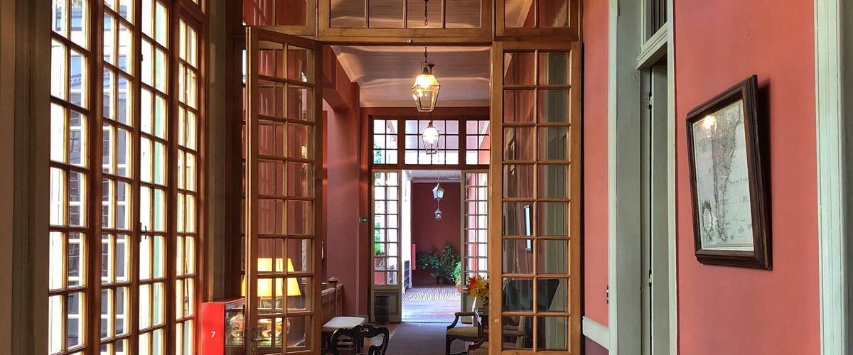 A hallway with large windows, wooden doors, and a radiator.