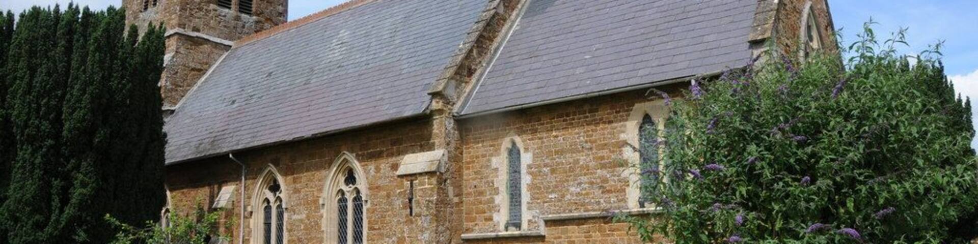 A historic church with a tower, arched windows, and a grassy cemetery.
