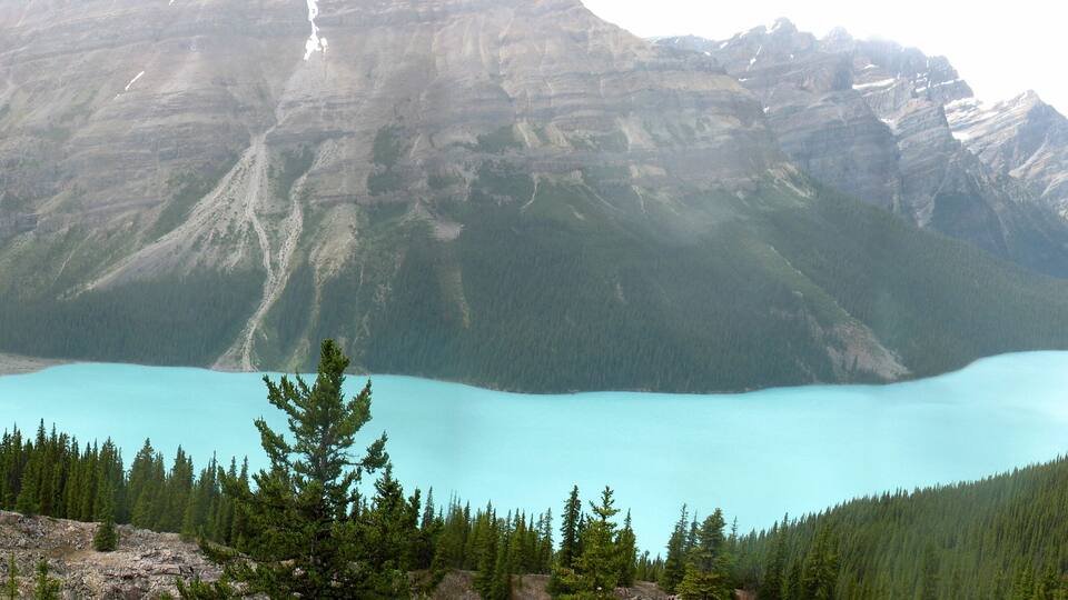 A turquoise lake surrounded by forested mountains.