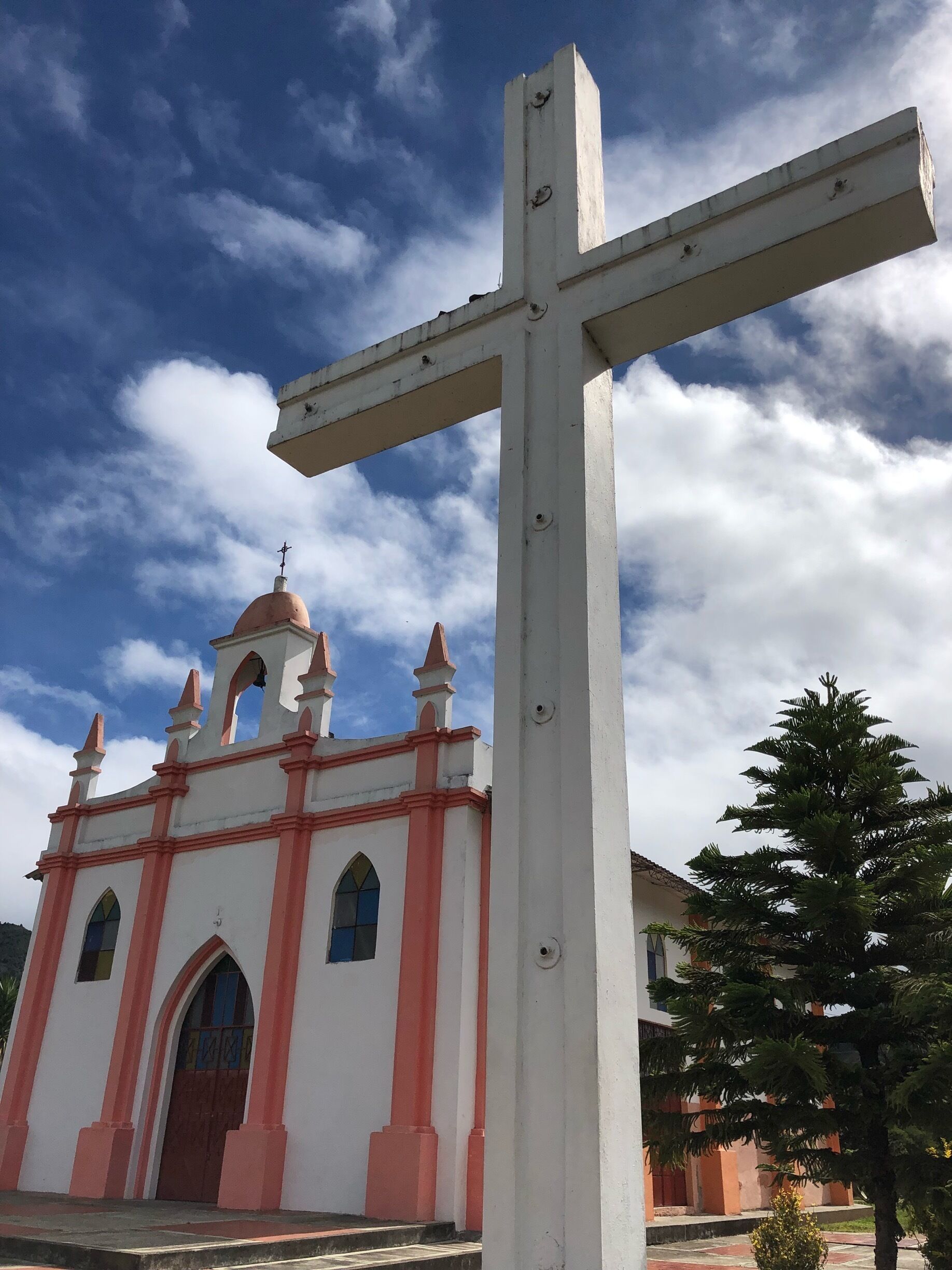 A church with a large white cross in front.